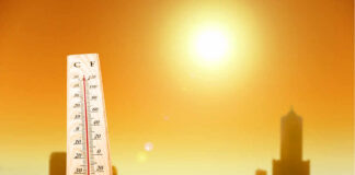 A thermometer held against a sunset city skyline