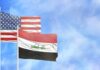 Flags of the United States and Iraq waving against a blue sky