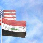 Flags of the United States and Iraq waving against a blue sky
