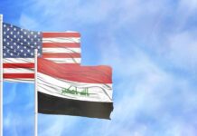 Flags of the United States and Iraq waving against a blue sky