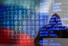 A hooded figure working on a laptop with binary code in the background