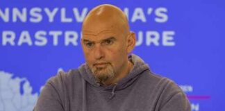 Man in a hoodie with arms crossed, looking serious in front of a presentation background