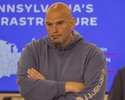 Man in a hoodie with arms crossed, looking serious in front of a presentation background