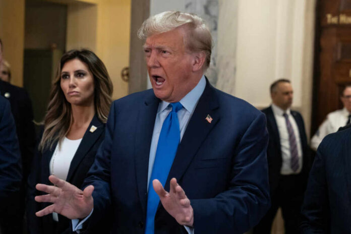 A man in a suit passionately speaking in a government building with a woman beside him