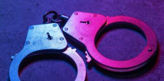 Close-up of metallic handcuffs illuminated with neon lights
