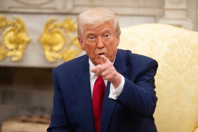 A man in a blue suit and red tie pointing while seated