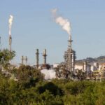 Industrial refinery with smoke stacks and visible flames