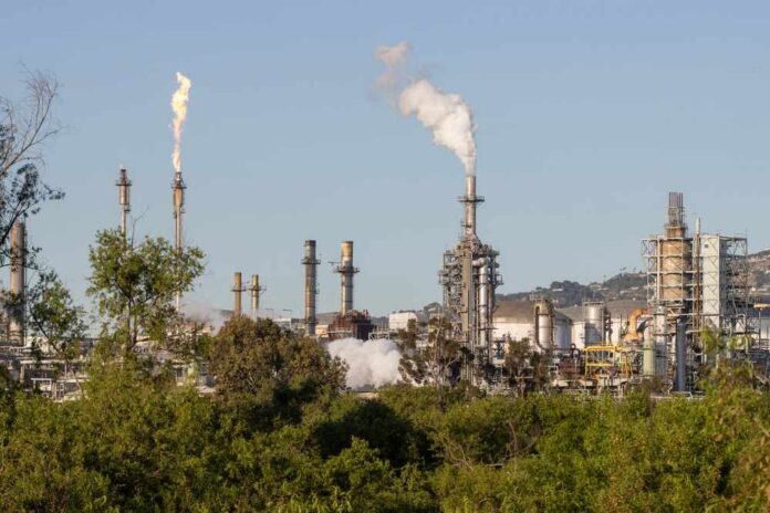 Industrial refinery with smoke stacks and visible flames