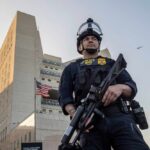Police officer in tactical gear standing in front of a building