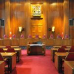 Generational Battle: Will Trump Reshape the Court Again? Interior view of a courtroom with wooden paneling and red seating