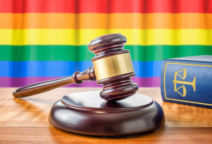 shutterstock_291401900.jpg A wooden gavel on a table with a rainbow flag in the background