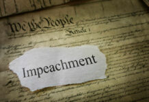 A torn piece of paper with the word 'Impeachment' on an old document background