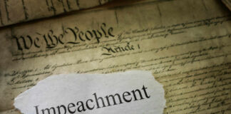 A torn piece of paper with the word 'Impeachment' on an old document background