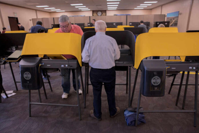 shutterstock1664852455jpg Individuals casting votes at a polling station with electronic voting machines
