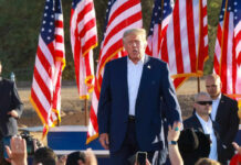 Trump’s Public Tributes Draw Major Attention A speaker at a political rally surrounded by American flags and an engaged crowd
