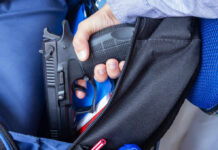 A hand holding a handgun partially visible in a backpack