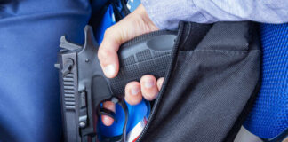 A hand holding a handgun partially visible in a backpack