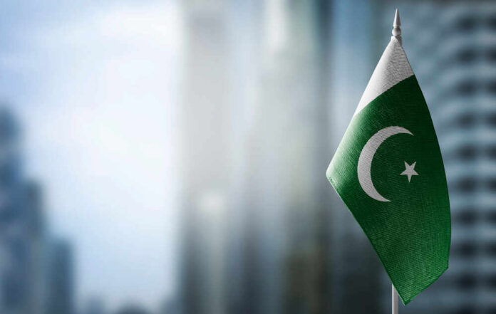 Flag of Pakistan waving in a blurred urban background