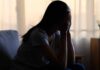 A silhouette of a person sitting with their head in their hands, conveying distress