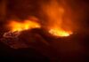 Aerial view of a volcanic eruption with flowing lava at night