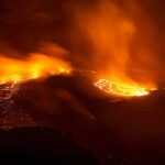 Aerial view of a volcanic eruption with flowing lava at night