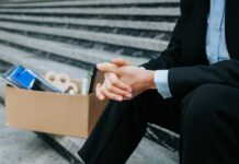 A person in business attire sitting on steps with a cardboard box of belongings
