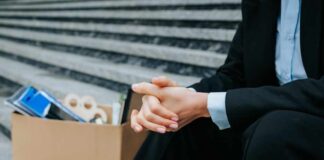 A person in business attire sitting on steps with a cardboard box of belongings