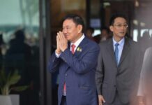 A man in a suit performing a traditional greeting gesture