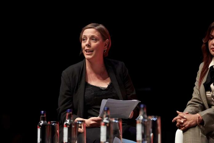 A woman speaking at a panel discussion with a focused expression