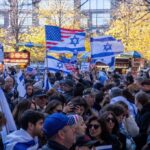 Crowd waving Israeli and American flags at a city rally