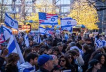 Crowd waving Israeli and American flags at a city rally