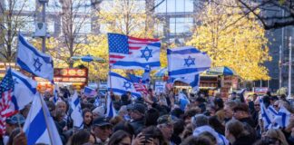 Crowd waving Israeli and American flags at a city rally