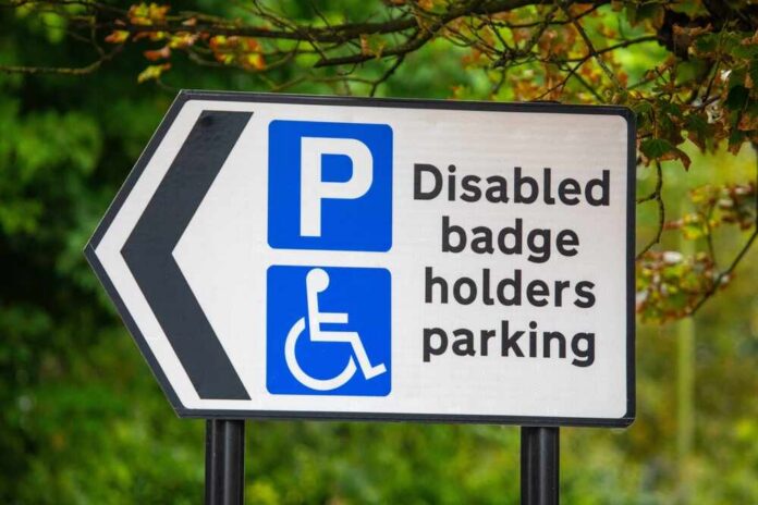 Close-up,Of,A,Disabled,Badge,Holders,Parking,Sign,In,The Disabled parking sign with left arrow