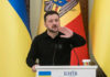 Ukrainian leader speaking at a podium with national flags in the background