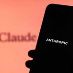 A hand holding a smartphone displaying the word 'ANTHROPIC' against a blurred background
