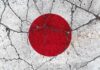 Japanese flag with a red circle on a white background waving against a blue sky