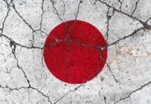 Japanese flag with a red circle on a white background waving against a blue sky