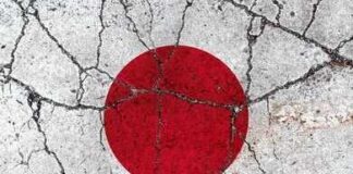 Japanese flag with a red circle on a white background waving against a blue sky