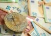 Fake Charity Funnels Cash To Hamas Bitcoin coin on scattered euro banknotes