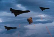 Three military drones fly through a cloudy sky amid anti-air fire