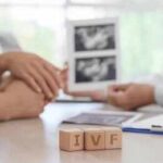 Couple consults doctor with ultrasound images and IVF blocks on desk
