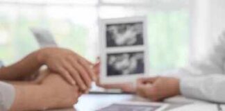 Couple consults doctor with ultrasound images and IVF blocks on desk