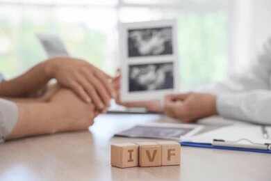 Couple consults doctor with ultrasound images and IVF blocks on desk