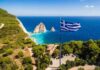 Greek flag overlooking a coastal cliff and turquoise sea