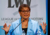 A female politician speaking passionately at a podium during a conference