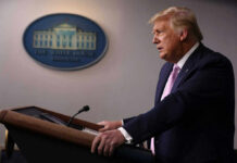 A government official speaking at a podium during a press conference at the White House