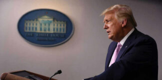 A government official speaking at a podium during a press conference at the White House