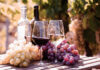 Digital Tax Fight Targets French Wine Two glasses of wine beside fresh grapes in a vineyard