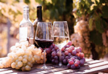 Digital Tax Fight Targets French Wine Two glasses of wine beside fresh grapes in a vineyard
