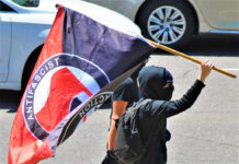Antifa Sting Explodes in Minneapolis Individual holding an antifascist flag during a protest